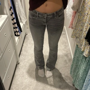 Grå bootcut jeans från Gina Tricot - Gråa lågmidjade bootcut jeans från Young Gina. Fickor bak med låtsas knappar (det är vanliga fickor), vita synliga sömmar. Säljer pga att de har blivit för små!💛
