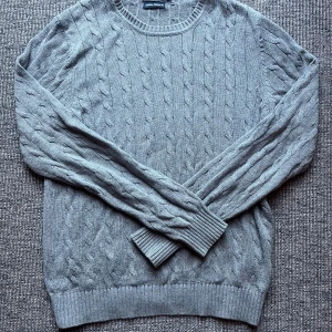 Grå kabelstickad tröja East West S - Kabelstickad grå tröja från East West i storlek S. Klassisk rund halsringning och ribbade muddar vid ärmslut och nederkant. Perfekt för lager-på-lager och chill höst- eller vinterstil. Nypris 900kr. Skickar inom 1-2 dagar. Svarar snabbt vid frågor och funderingar. Kom med prisförslag😄