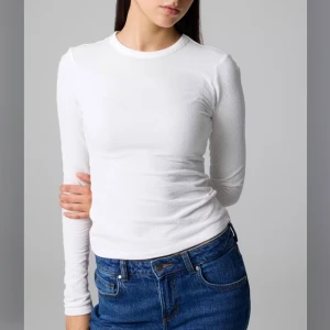 Vit långärmad basic tröja - En stilren vit långärmad tröja med rund halsringning. Tröjan är figurnära och tillverkad i ett bomullstyp ganska likt frotté men stretchigt material. Passar även S. Aldrig använd med prislapp kvar!