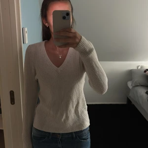 Beige ribbad stickad tröja V-ringad - Säljer en beige stickad tröja med ribbad struktur och V-ringning. Tröjan har lång ärm och sitter snyggt med en normal passform. Perfekt att matcha med jeans för en enkel och stilren look. Storlek M men passar s/xs!