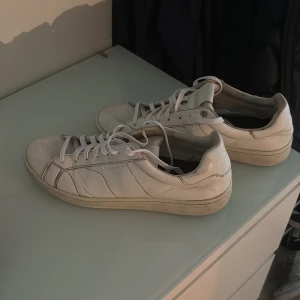 Vita sneakers från Björn Borg - Klassiska vita sneakers från Björn Borg med stilrena sömmar och rund tå. Skorna har snörning och är tillverkade i skinn med vit sula. Perfekta för dig som gillar en clean och enkel look till vardags.
