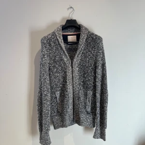 Gråmelerad kofta från Banana Republic - Säljer en gråmelerad kofta från Banana Republic Heritage Collection. Koftan har dragkedja framtill, två fickor och är stickad i en blandning av svart och vit. Perfekt för lager-på-lager och har en avslappnad, mysig känsla. Väldigt varm och är helt defekt fri. Hör av er vid frågor eller fler bilder