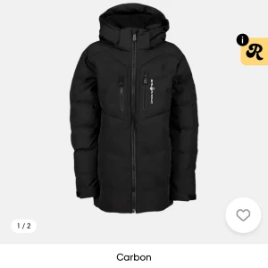 Svart pufferjacka från SAIL Racing  - Säljer en svart pufferjacka från SAIL Racing med huva och flera praktiska fickor med dragkedja. Jackan har en lång passform och är perfekt för kalla dagar. Ord pris på jackan är 3 500 kronor men säljer för 1800