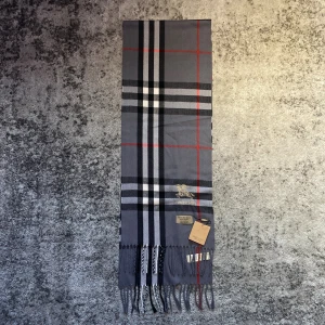 Grå Burberry halsduk - Skön halsduk i nytt skick, passar perfekt till kyligare dagar då den värmer och är elegant samtidigt. Orginalkartong mm medföljer.