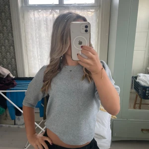 Grå stickad tröja från ONLY - Superfin ljusgrå stickad tröja från ONLY med korta puffärmar och rund hals. Tröjan är croppad och har en mjuk, skön känsla. Använt en gång 