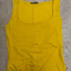 Gul linnetopp från Zara - Snygg gul linnetopp från Zara med breda axelband och rundad halsringning. Perfekt för dig som vill ha en färgklick i garderoben. Ett skit snyggt linne som sitter perfekt på kroppen, storlek S men kan även funka för xs, endast använd ett par gånger. 