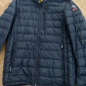 Svart lättviktsdunjacka Parajumpers - Säljer en svart lättviktsdunjacka från Parajumpers med quiltad design och dragkedja framtill. Jackan har tre fickor med dragkedja och en patch på ärmen. Insidan är silverfärgad och jackan är perfekt för kyliga dagar.