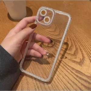 Mobilskal iPhone 12  - Snyggt och transparent skal med glitterkant, designat för iPhone 13. Ger bra skydd mot repor och stötar samtidigt som telefonens design syns. Skalet är i nyskick utan synligt slitage eller defekter. Perfekt för dig som vill ha både stil och funktion.