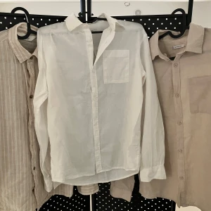Tre skjortor i linne och bomull - Säljer tre skjortor i relaxed stil, två i beige toner och en i vitt. En skjorta är randig beige/vit, de andra enfärgade. Alla har klassisk krage, bröstficka och knäppning framtill. Perfekta för en chill och stilren look. 164cm CUBUS x 2 och H&M är 158cm. Knappt använda! 