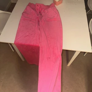 Juicy couture set - Säljer ett par rosa mjukisbyxor med bred resår och snörning i midjan. Byxorna har två stora fickor fram och två bakfickor med knapp. Materialet är mjukt och skönt, perfekt för chill dagar. Snygg detalj med broderad logga på ena fickan.