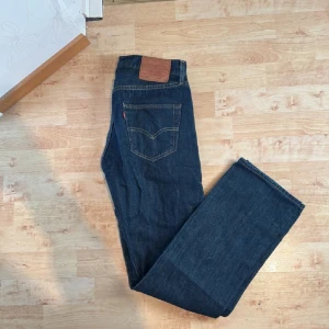 Levi's 501 jeans mörkblå W30 L32 - Klassiska Levi's 501 jeans i mörkblå denim. Rak passform med fem fickor och ikonisk läderpatch bak i midjan. Snygga kontrastsömmar och tidlös stil som funkar till allt. Perfekta för dig som gillar en clean och autentisk look.