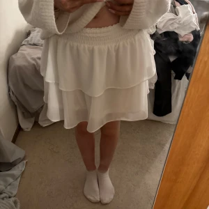 Vit volangkjol från Chelsea XS - Supersöt vit kortkjol från Chelsea i storlek XS. Kjolen har två lager volanger och bred resår i midjan för en bekväm passform. Perfekt för dig som gillar en feminin och luftig stil. Materialet känns lätt och flowy. Fungerar som både kjol och topp!🤍