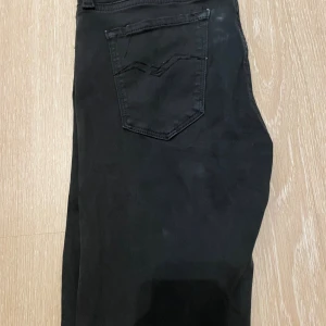 Svarta skinny jeans från Replay - Säljer ett par svarta skinny jeans från Replay med klassisk femficksdesign och diskret broderad bakficka. Jeansen har smal passform och är tillverkade i stretchigt jeansmaterial för en bekväm känsla. Perfekta för dig som gillar stilrena och tajta jeans.