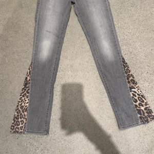 Grå Levis jeans med leopard-detaljer - unika gråa levis med leopard mönster på sydda. passar väldigt low waist på mig och är i storlek 24 (24 inch). har inga defekter och passar jätte fint!❣️knappt använda