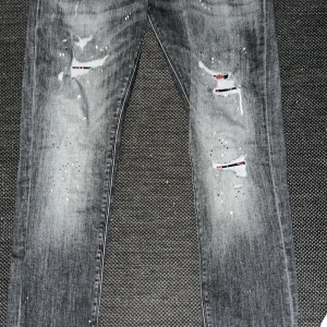 Svarta distressed jeans med färgstänk - Säljer ett par svarta jeans från Jack Jones med slitna detaljer, hål och coola färgstänk. Jeansen är ganska sällsynta. Jeansen har en smal passform och klassisk femficksdesign. Perfekta för dig som gillar en edgy streetstil och vill sticka ut lite extra. Väldigt unika jeans passformen är perfekt. Hör av dig vid pris eller snnat