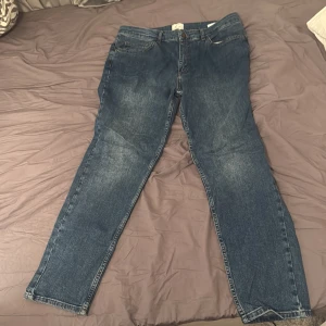 Blå jeans från Plain Units - Snygga blå jeans från Plain Units med klassisk femficksdesign och raka ben. Jeansen har en mellanblå tvätt med lätt slitning och är tillverkade i bomull. Perfekta för en avslappnad och stilren look.