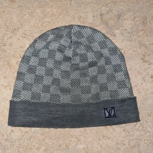 Grå rutig mössa - Snygg grå mössa med klassiskt rutigt mönster och vikt kant. Tillverkad i mjukt stickat material som känns skönt mot huden. Perfekt accessoar för att lyfta din look under kyliga dagar.