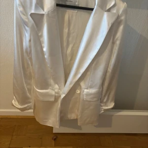 Vit kavaj i Satin från Mex - Snygg vit kavaj från Mex, tyvärr sliten höger axel men syns inte på eller med håret nere. Därav priset. 