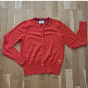 Kofta - Snygg röd/orange kofta från Holly & Whyte by Lindex i storlek S. Mjukt material. Endast använd 1 gång. Perfekt till hösten.