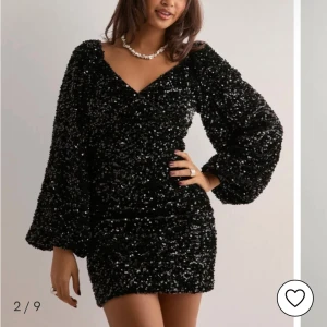 Svart glittrig nyårsklänning med puffärm - Säljer en svart glittrig nyårsklänning med v-ringning och puffiga långärmar! Köptes på nelly och använd endast 1 gång.