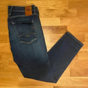 Replay anbass hyperflex w34 - Säljer dessa riktigt snygga mörkblåa replay anbass hyperflex jeansen! Dem är i mycket bra skick överlag förutom nån liten missfärgning på benet (skriv för bild), storleken är W34 och L30,  måtten är 97 cm totallängd, 44 cm midjelängd och 20 cm tvärs över knät, hör gärna av dig vid frågor!