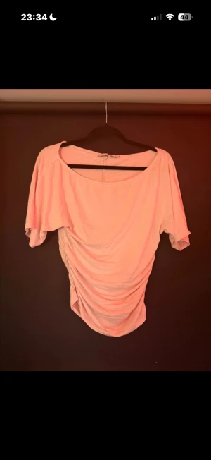 Ljusrosa omlott topp från 157 - Säljer en ljusrosa topp från 157 i storlek S. Toppen har omlott-effekt med snygg rynkning på sidan och bred halsringning. Materialet är mjukt och känns som bomull. Perfekt för dig som gillar en feminin och chill stil.