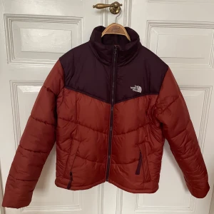 The North Face Dunjacka, 1996 Retro Nuptse, stlk M - Snygg pufferjacka från The North Face i storlek M. Mycket bra skick. Jackan har hög krage, dragkedja framtill och två fickor med dragkedja. Perfekt för kalla dagar och riktigt skön att bära. Logga på bröstet och ryggen. 