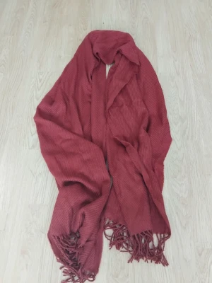 Röd halsduk med fransar från Pieces - Mysig röd halsduk från Pieces med diskret ribbad struktur och fransar i ändarna. Perfekt att svepa runt halsen för extra värme och stil. Stor och mjuk, passar dig som gillar att sticka ut med en färgklick i outfiten.