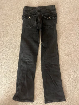 Mörkgrå bootcut jeans - Mörkgrå jeans från lager 157 med klassisk femficksdesign och snygga ficklock med knapp bak. Modellen har bootcut-ben och normal passform, vilket ger en schysst siluett. Jeansen är tillverkade i jeansmaterial och har en stilren look som funkar till många outfits. Säljer pga för små. Dom är storlek short XXS