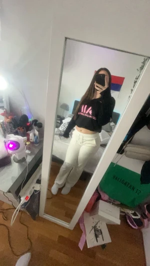 Svart hoodie med rosa tryck AIM - Svart croppad hoodie från AIM med rosa tryck framtill och halv dragkedja. Tröjan har långa ärmar och en skön, loose passform. Perfekt för dig som gillar streetstyle och vill ha något bekvämt men ändå snyggt.