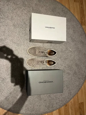 Grå mockasneakers från Vagabond - Säljer ett par stilrena sneakers från Vagabond i grå mocka med vita sulor. Skorna har klassisk rund tå, snörning och en clean design som passar till det mesta. Perfekta för dig som gillar en enkel men snygg look.