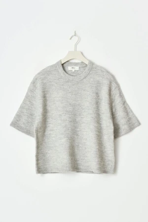 Grå stickad tröja från Gina - Mysig ljusgrå stickad tröja från Gina med korta ärmar och rund halsringning. Tröjan har en loose passform och ribbade kanter vid ärmslut och nederkant. Perfekt för lager-på-lager under hösten och vintern.