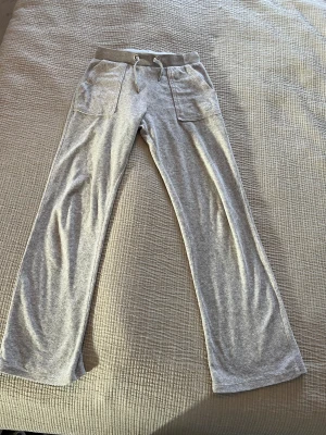 Juicy Couture str 9/10 - Säljer ett par grå mjukisbyxor med bred resår och snörning i midjan. Byxorna har två stora fickor framtill och är tillverkade i mjukt material som känns skönt mot huden. 