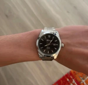 Svart och silver klocka från Doventi  - Stilren klocka från Doventi med svart urtavla och silverfärgade detaljer. Klockan har en klassisk rund form, datumvisning och länkarmband i metall. Perfekt accessoar för dig som gillar en clean och tidlös look.