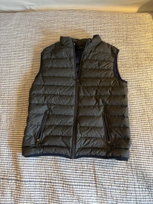Grå dunväst från Polo Ralph Lauren - Säljer min Polo Ralph Lauren väst som är grå och sprillans ny. Säljer då den snart är för liten, ny kostar den 1899kr och säljer 799kr, tror den är använd Ksk 2 gånger och där efter priset, den är självklart äkta, den har inget strl men passar mellan 158-168 cm vilket motsvarar XS.pris ej hugget i sten!!