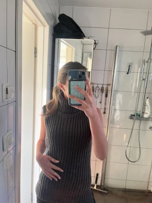 Grå stickad polotröja från H&M - Säljer en chunky grå stickad polotröja från H&M i storlek XS. Tröjan är ärmlös med bred polokrage och grov ribbad struktur, perfekt för lager-på-lager under höst och vinter. Supermysig och trendig att styla med jeans eller kjol.