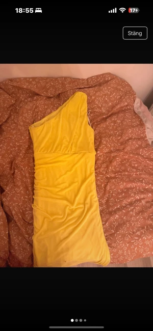 Gul one shoulder långklänning - Snygg gul långklänning med one shoulder-design och draperad effekt längs sidan. Klänningen har en figurnära passform och är tillverkad i ett mjukt, stretchigt material som ger en bekväm känsla. Perfekt för dig som vill sticka ut med en färgstark look.