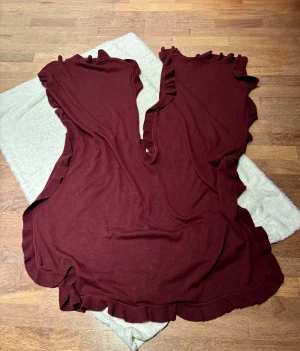 Vinröd halsduk med volangkant - Säljer en vinröd halsduk / schal  med snygga volangdetaljer längs kanterna. Mjuk stickad känsla. Perfekt för dig som gillar en chill och unik look med extra detaljer.