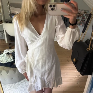 Vit klänning i linne - Aldrig använd!❌Superfin vit kort omlottklänning med långa puffärmar och volangkant nertill. Klänningen har knyt i midjan och v-ringad hals. Perfekt för sommarens alla tillfällen och ger en fräsch och stilren look.