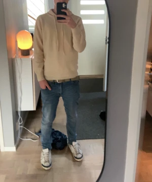 Beige merinoull hoodie - Snygg beige hoodie med huva och snörning i halsen. Tröjan har långärmade ärmar och ribbade muddar vid ärmslut och nederkant. Perfekt för chill dagar och enkel att matcha med jeans eller joggers. Mjuk och skön känsla tack vare merino materialet. Märket är lite oklart men jag köpte den för ca 650 spänn på nätet. Storlek M. Vid frågor eller funderingar hör av dig!