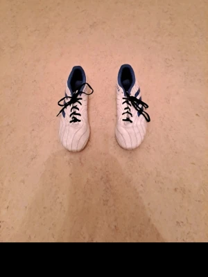 Vita Copa fotbollsskor med blå detaljer - Jag säljer ett par fotbollsskor i storlek 41 som är i mycket bra skick. De är väl omhändertagna och ser nästan nya ut. Perfekt för dig som vill spela fotboll med bra skor till ett bra pris.  Priset är 200 kr, vilket jag tycker är ett riktigt bra pris med tanke på skicket och att det är fotbollsskor. Jag är öppen för snabba affärer!  Tveka inte att höra av dig om du är intresserad eller har några frågor. Först till kvarn gäller!