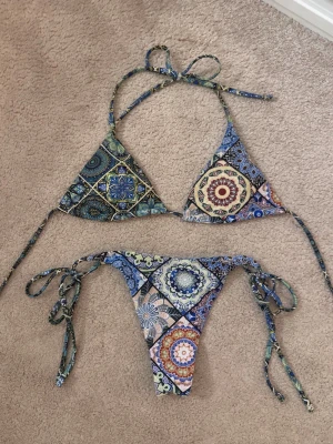 Färgglad bikini - Säljer en snygg bikini med färgglada mönster i blått, grönt, gult och rött. Klassisk trekantsmodell upptill och knytband både på toppen och trosan. 