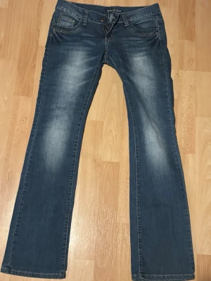 Blå bootcut jeans med nitar - Snygga blå bootcut jeans med slitningar och coola nitar vid fickorna. ( de är ganska tajta )
