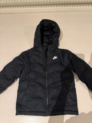 Svart pufferjacka från Nike  - Säljer just nu en svart pufferjacka från Nike då jag knappt har använda den pga växt ur den. Jacka har bra skick då jag har tagit väl hand om den! Storleken i jackan är 147-158 men passar även lite längre! Inköpt för cirka 750 kr 