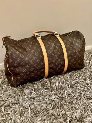 Louis Vuitton Keepall Bandoulière 50 i monogramcanvas.  - Säljer nu min extremt fina Louis Vuitton väska. Som är perfekt för dig som ska ut och resa eller bara vill se lyxigare ut i vardagen. Väskan har blivit lite solblekt och på handtagen axelremmen medkommer ej! Därför jag säljer billigt! Hör av dig vid intresse