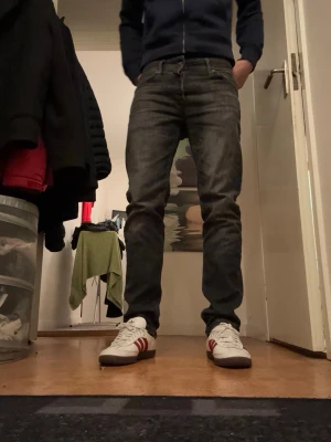 Mörkgrå jeans från Jack and Jones 30/32 - Säljer ett par mörkgrå jack and Jones jeans med klassisk femficksdesign och knappgylf. Jeansen har en slim passform och raka ben, tillverkade i slitstark bomullsdenim. Perfekta för dig som gillar en clean och tidlös look.