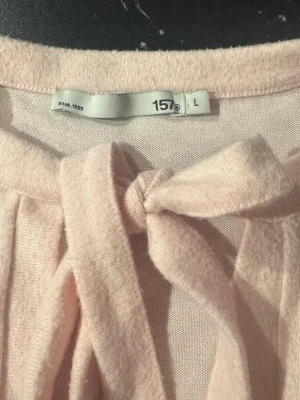 Ljusrosa kofta med knyt från Lager 157 - Söt ljusrosa kofta från Lager 157 med knytband framtill vid halsen. Koftan har långa ärmar och är gjord i ett mjukt, tunt material som känns skönt mot huden. Perfekt att slänga över en topp för en extra touch till din outfit.