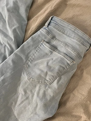 Ljusblå bootcut jeans - Säljer ett par ljusblå bootcut jeans med klassisk femficksdesign och normal passform. Jeansen har medelhög midja och bredare nertill väldigt sköna och stretchiga, använda 3 gånger