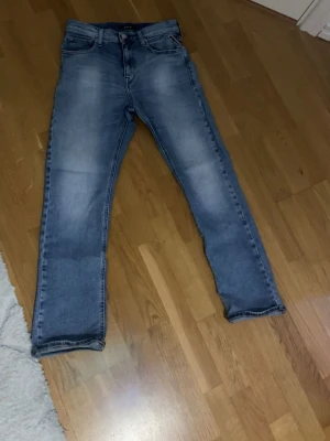 Replay ljusblå jeans straight fit - Säljer ett par ljusblå jeans från Replay i klassisk straight fit. Jeansen har fem fickor, normal passform och snygga slitningar framtill för en avslappnad look. Tillverkade i tåligt denimtyg som passar perfekt till vardagsstilen.