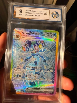 Pokémon Glaceon ex Alt Art sv8a 206 - Japanskt Pokémonkort från 2024, Glaceon ex Alt Art sv8a 206 Terastal Festival. Kortet är graderat Mint 9 av RaukCard och har en färgstark, holografisk design med Glaceon och kristallmotiv. Kortet är inneslutet i ett skyddande plastfodral.